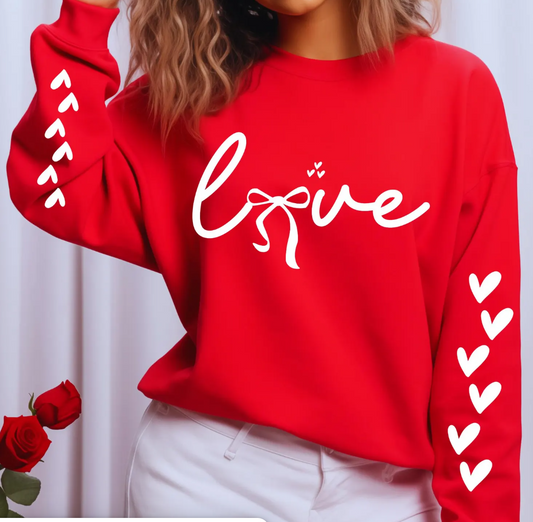 Red sweatshirt with 'love' text and heart designs on sleeves, worn by a person.