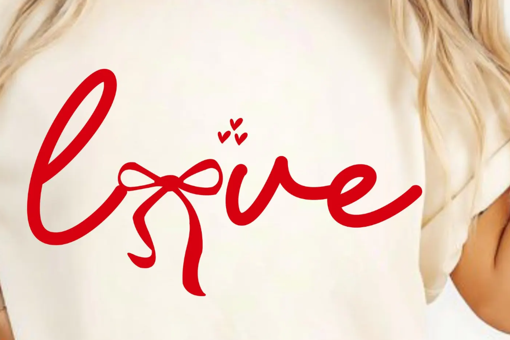 Person wearing a white shirt with 'love' written in red cursive text and a bow.